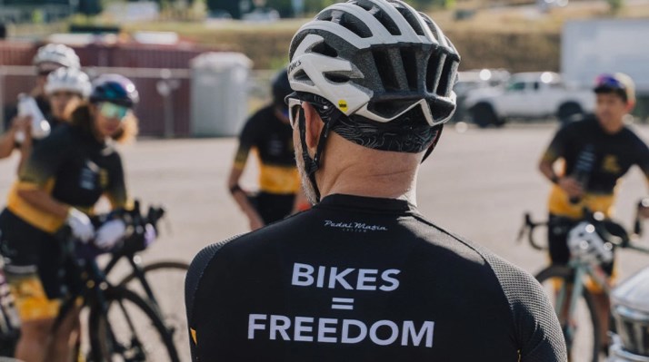 A cyclist with his back turned to the camera wearing a jersey that reads "Bikes equal Freedom"