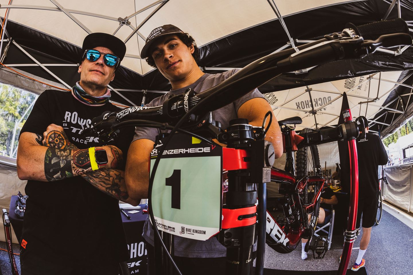 JT Evans and Tegan Cruz standing with the No. 1 race plate in the RockShox Trek Race Team pit.