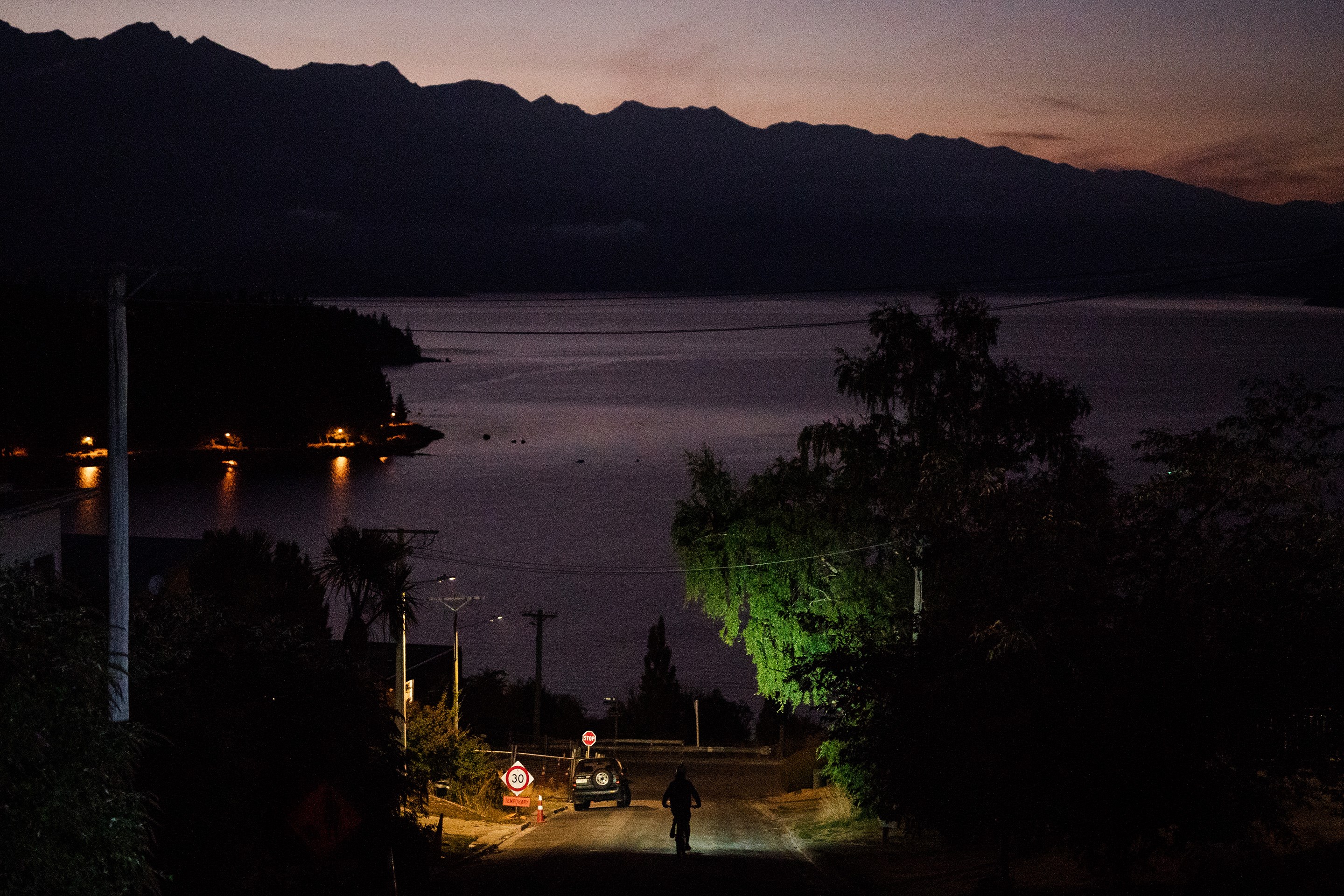 Riding a bicycle down a steep street at dusk