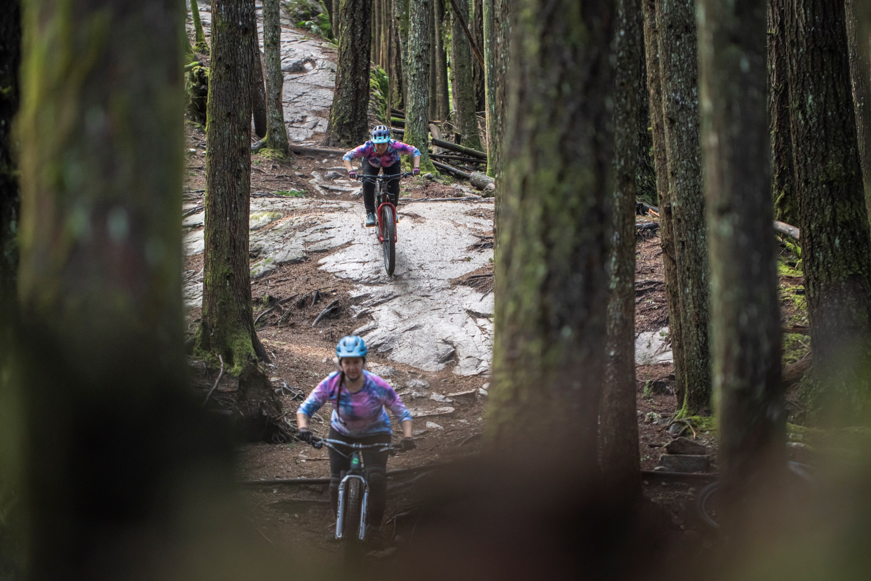 Courtney and Michele descent slickrock between trees