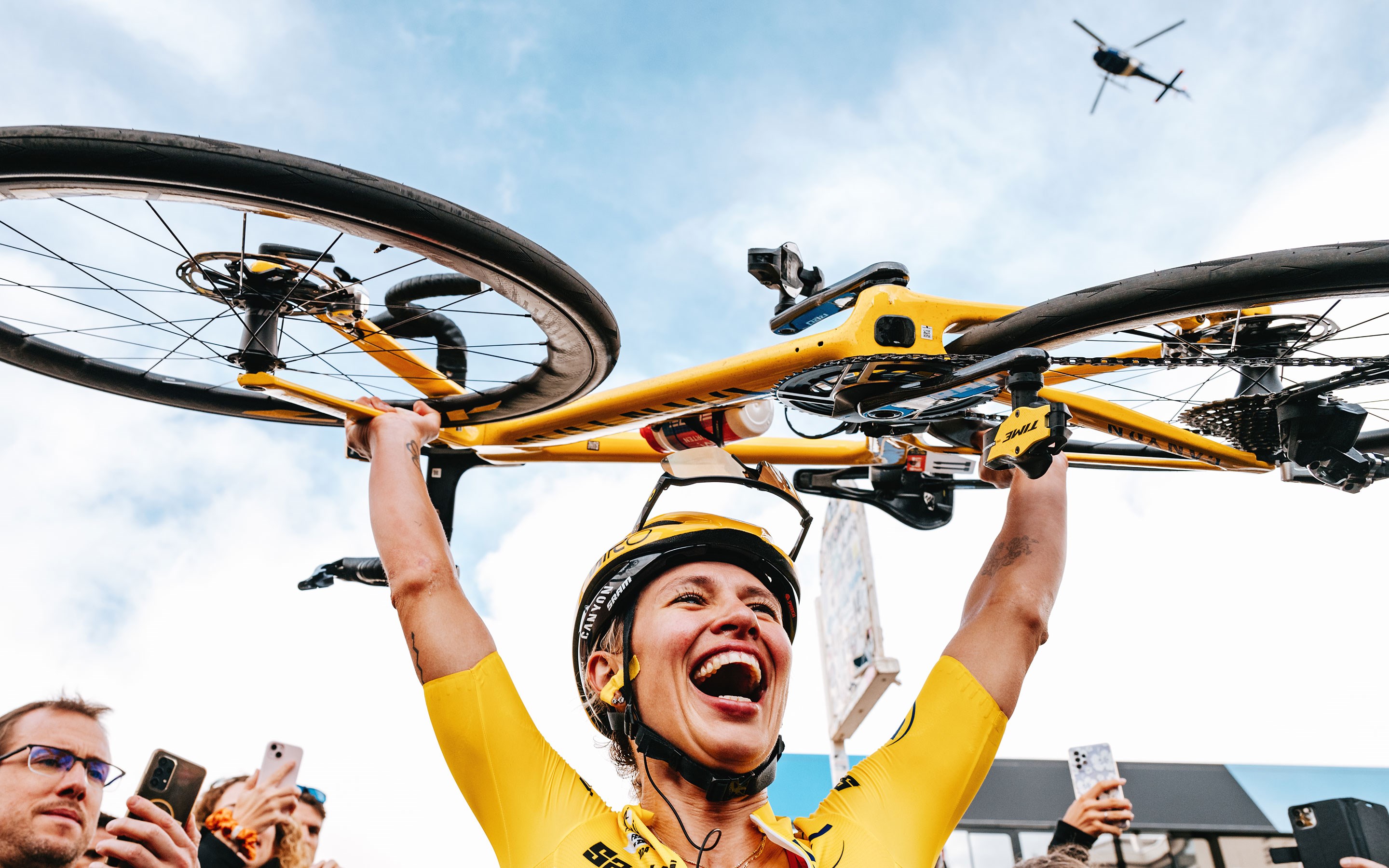 Kasia Niewiadoma lifts her bike over her head after winning the tour de France Femmes